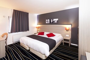 Ein modernes Hotelzimmer mit einem großen Bett, zwei Nachttischen mit Lampen, einem Schreibtisch und einem Stuhl.