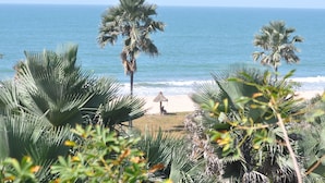 A beach with palm trees and a thatched structure. - Leo's Beach Hotel & Restaurant - Adults Only (Brufut)
