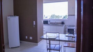 Una cocina equipada con refrigerador, microondas, estufa y un ventanal con vista a la ciudad.
