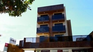 Un edificio de varios pisos con un diseño arquitectónico moderno, que cuenta con balcones y ventanas amplias.