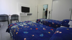 Habitació d'hotel amb dos llits, una televisió sobre una estant, un penjador i una porta que dona a un bany.