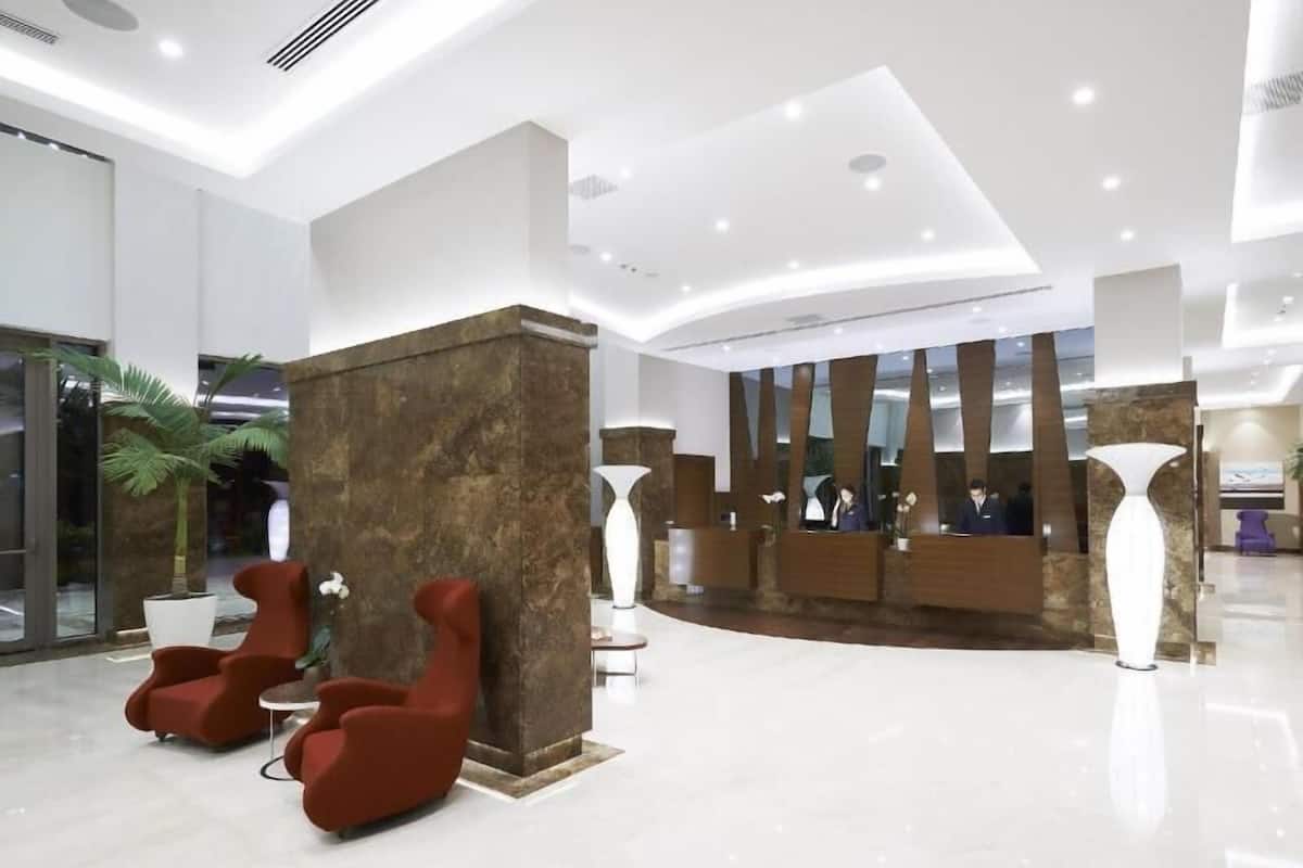 A modern lobby with a reception desk, seating area, and a large plant.