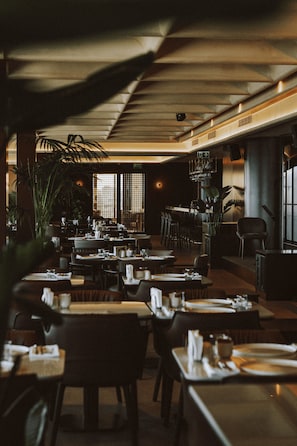 Een restaurant met gedekte tafels, stoelen en een bar.