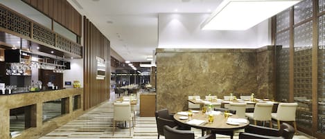A modern restaurant with a bar area, marble flooring, and a mix of wooden and stone decor.