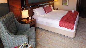 Een hotelkamer met een bed, een stoel, een nachtkastje, een lamp, een vaas met bloemen en een tijdschrift op een tafel.