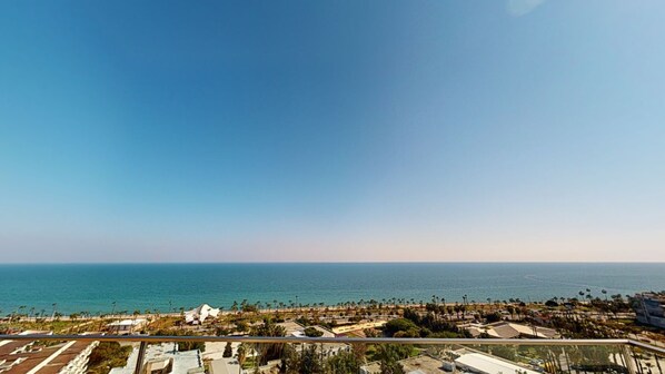 Une vue sur la côte, avec un ciel dégagé, une plage et un port de plaisance.