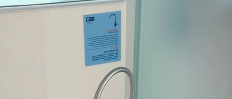 A bathroom with a water tap and a sign about sustainability.