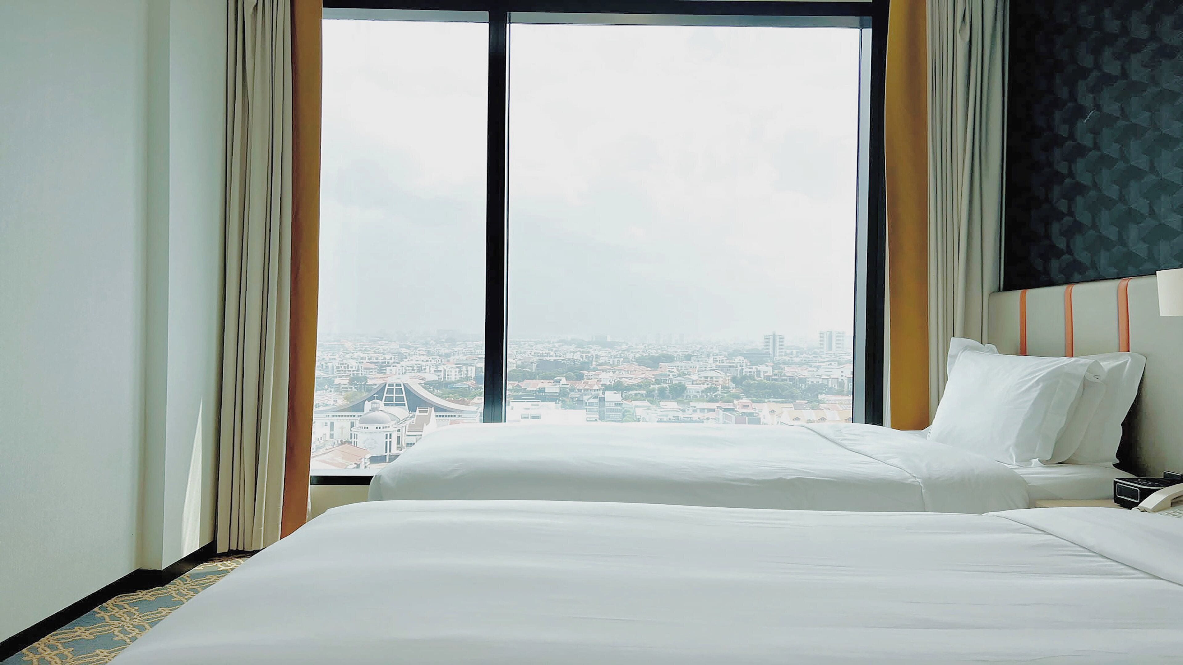 Ein Hotelzimmer mit großem Fenster, einem Bett und einem Nachttisch.