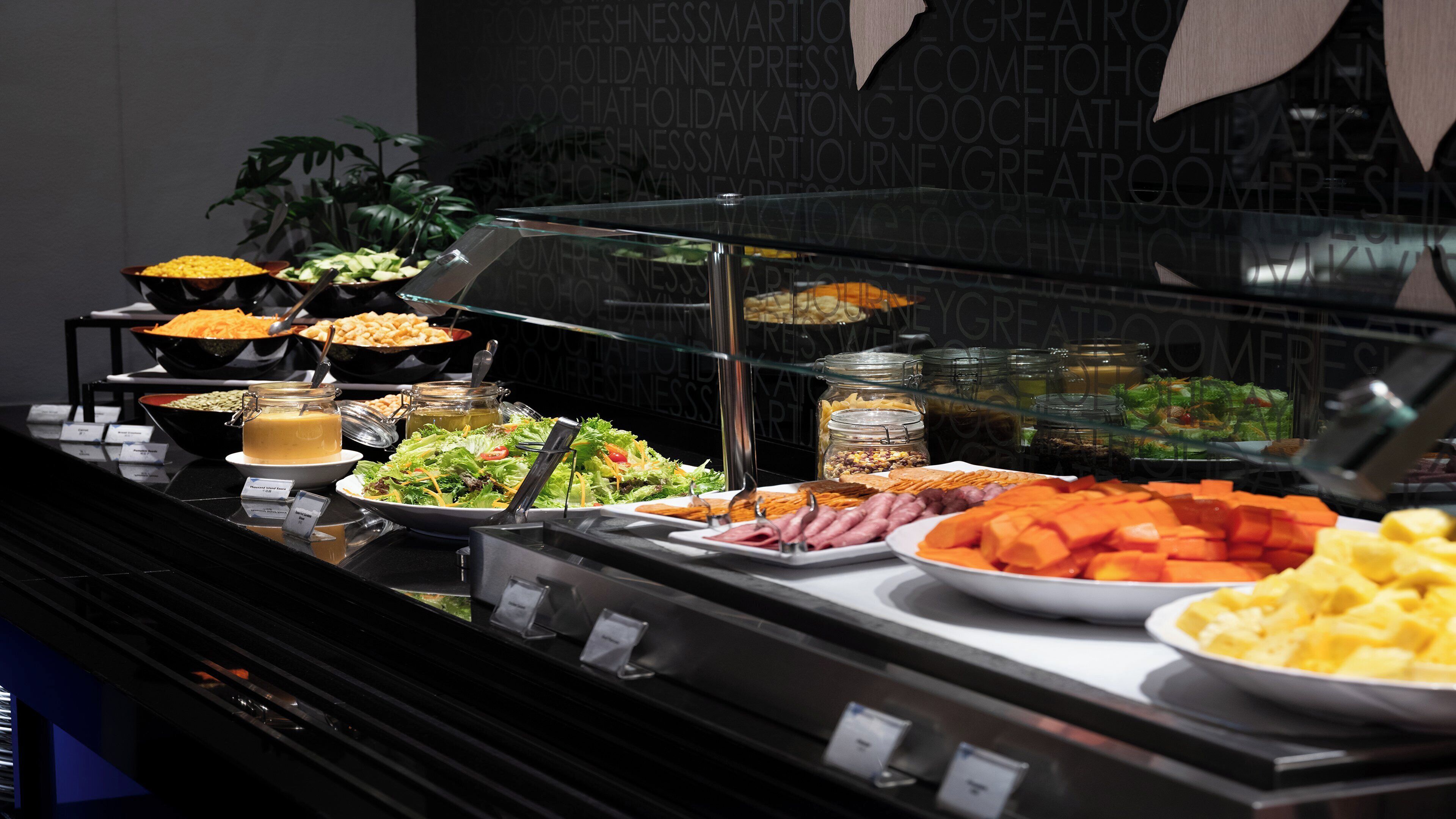 A buffet with various food items including salads, meats, and cheeses.