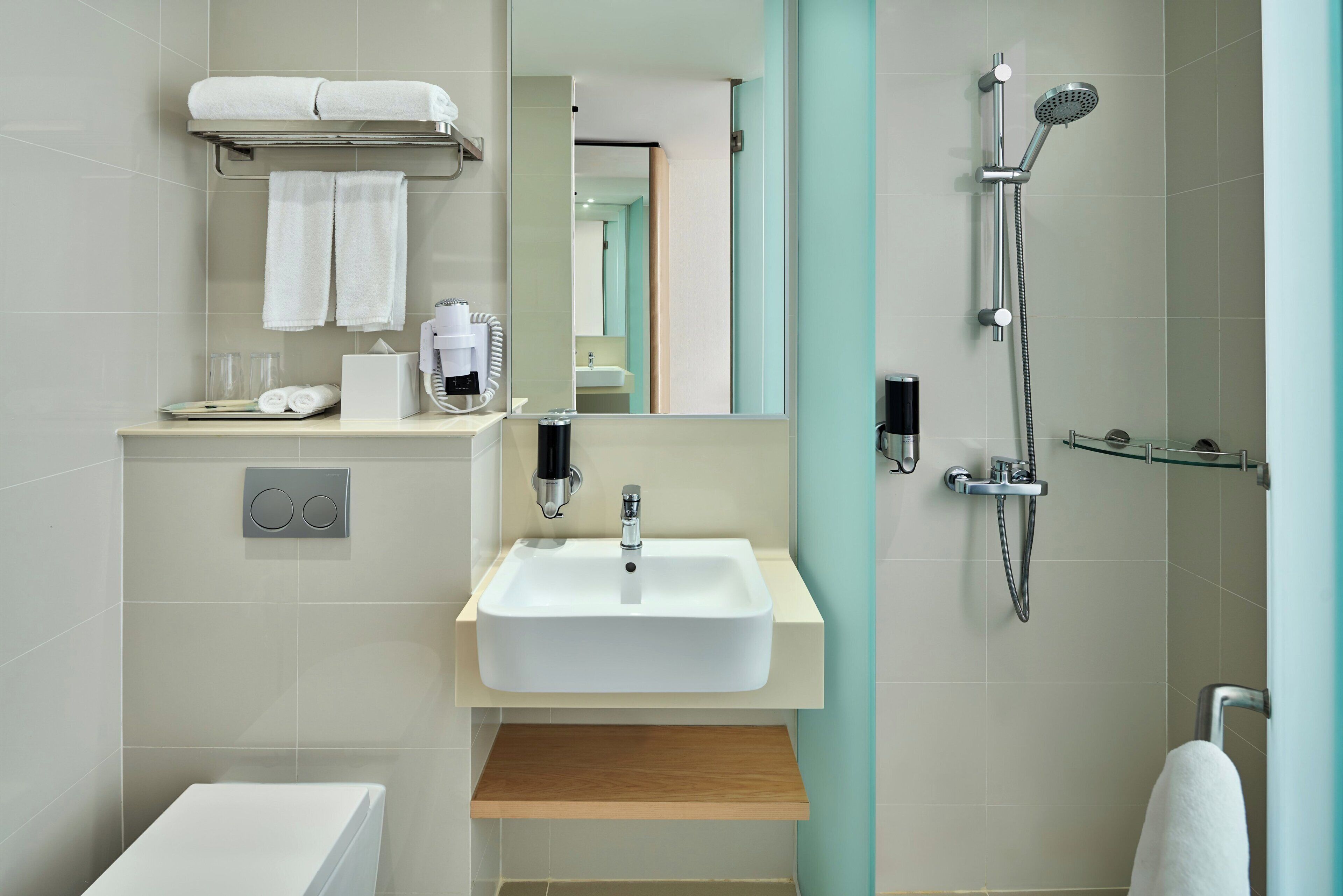 Un baño moderno con lavamanos, espejo, toallero, ducha e inodoro.