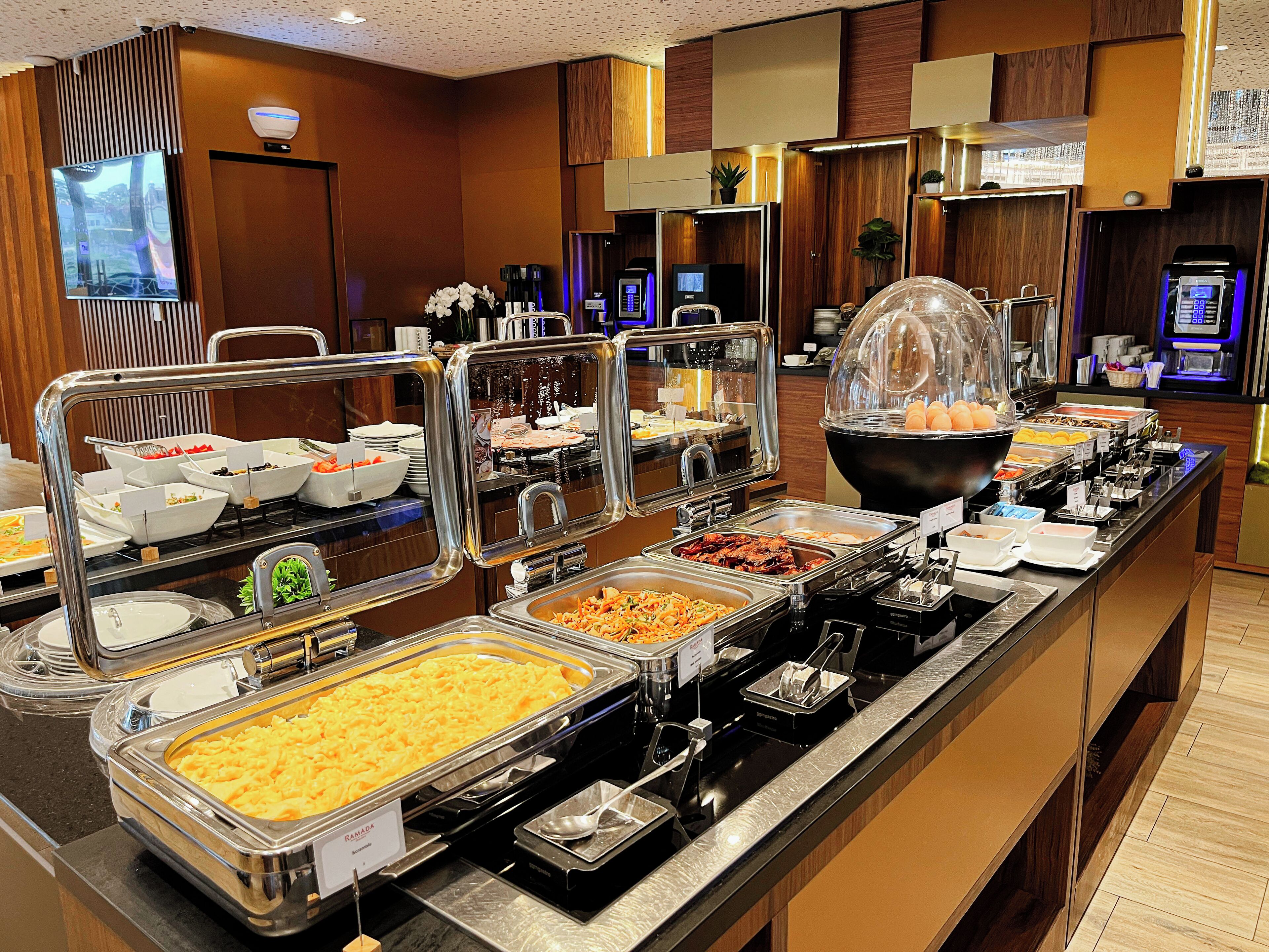 A buffet with various food options, including a large bowl of eggs, a tray of scrambled eggs, and several other dishes.