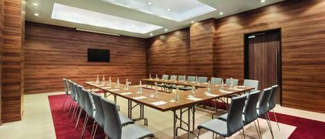 A conference room with a long table, chairs, and a red carpet.