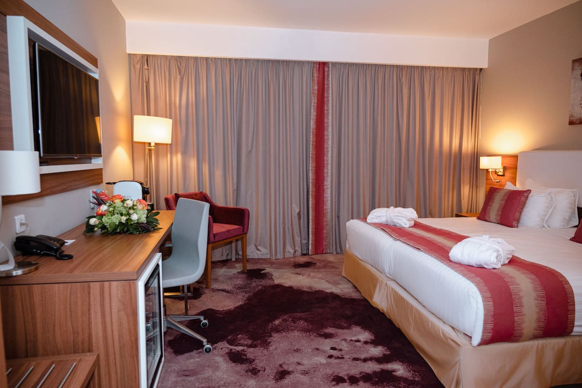 Una habitación de hotel con cama, escritorio, silla y cortinas.