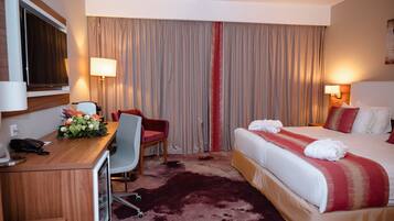 Una habitación de hotel con cama, escritorio, silla y cortinas.