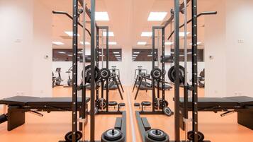 Ein Fitnessstudio mit Spiegelwänden, Krafttrainingsgeräten und Cardiogeräten.