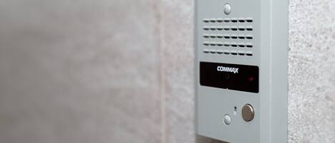 A wall-mounted security device with a display screen and buttons.