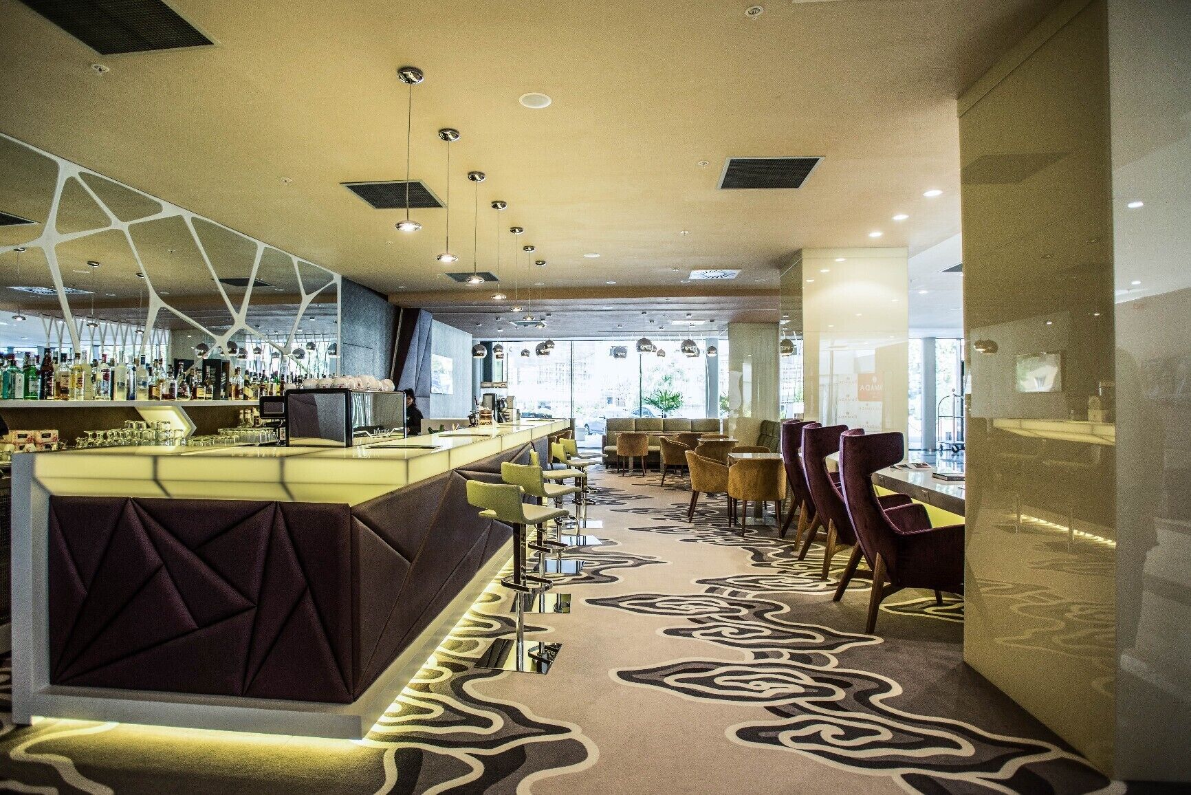 A modern bar area with a counter, seating, and a patterned carpet.
