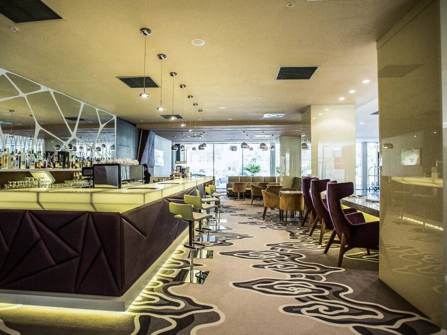 A modern bar area with a counter, seating, and a patterned carpet.