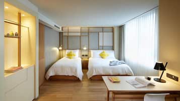 A hotel room with two beds, a desk, and a window with curtains.