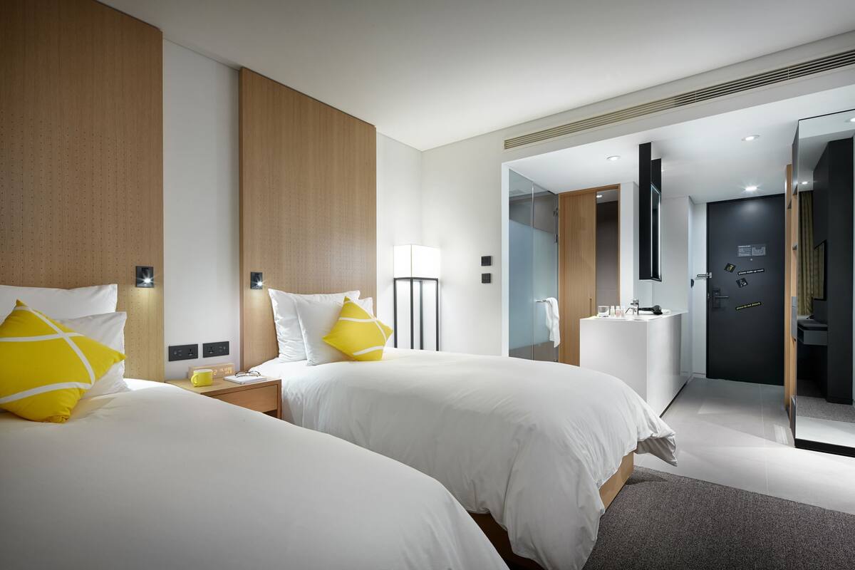 Een moderne hotelkamer met twee bedden, een badkamer en een inloopkast.