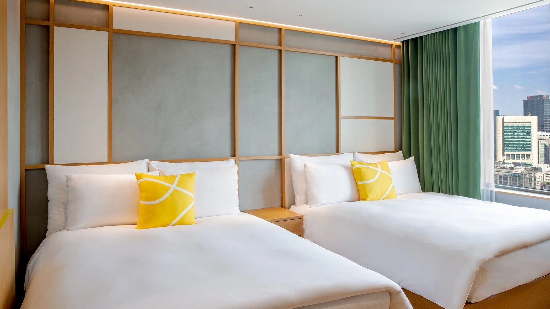 A hotel room with two beds, a city view, and a modern design.