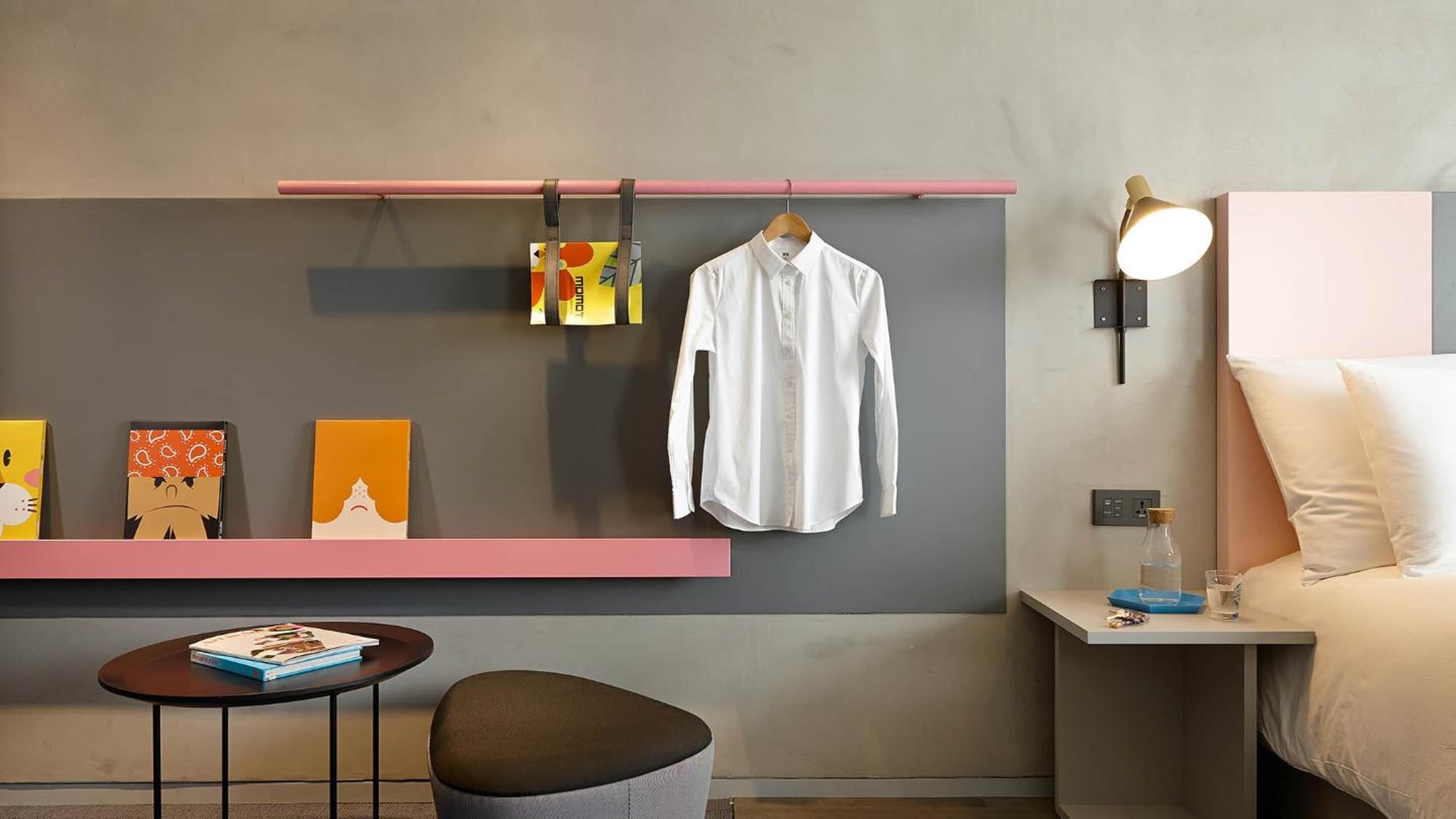 Una habitación de hotel moderna con una cama, mesita de noche y una pequeña mesa con un libro.