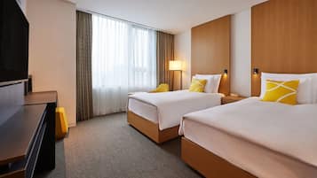 Habitación de hotel con dos camas, televisión, escritorio y lámpara.