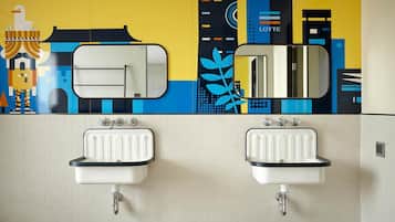 A bathroom with two sinks, a mirror, and a colorful mural on the wall.