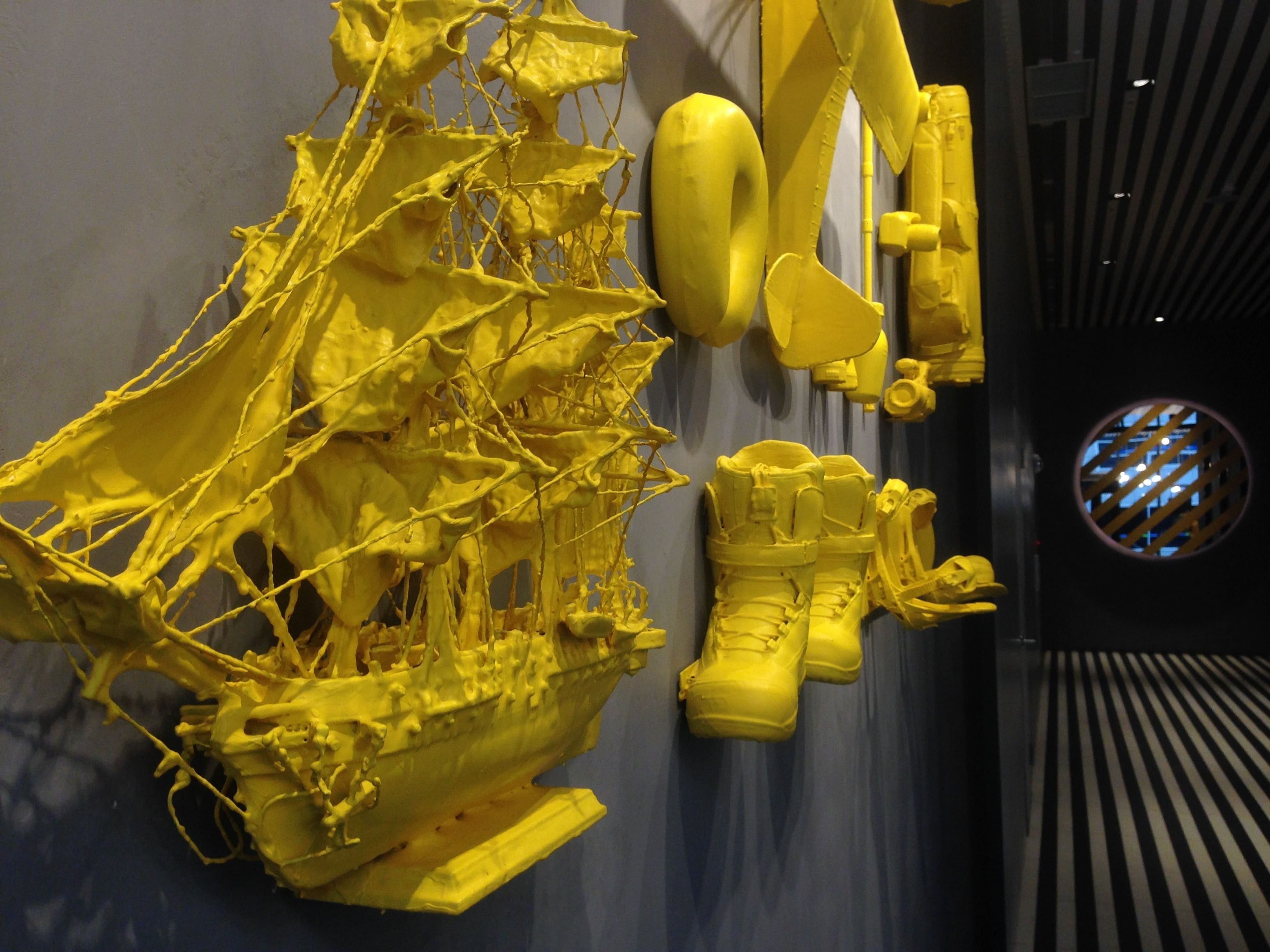 Une sculpture tridimensionnelle jaune, installée dans un espace intérieur moderne.