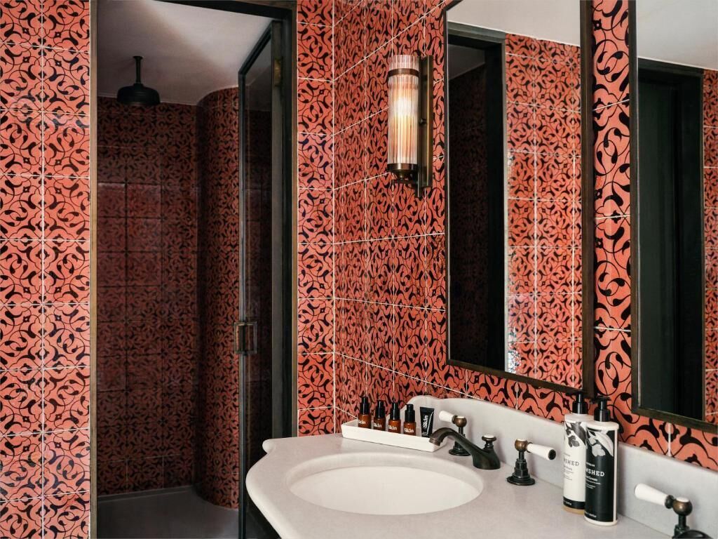 Une salle de bain avec un grand lavabo, un miroir et un espace douche.