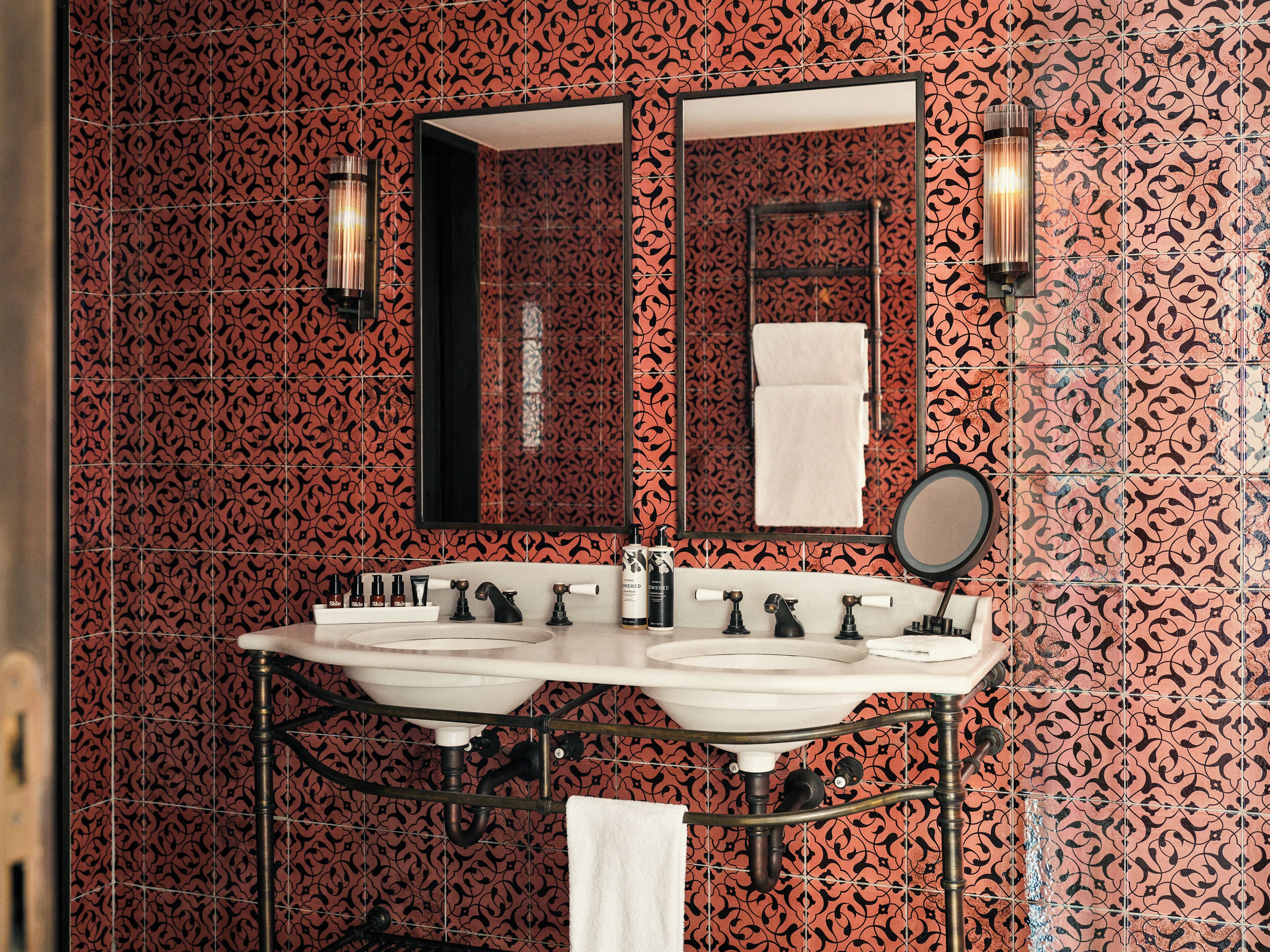 Un baño con tocador doble, un espejo grande y un perchero para toallas.