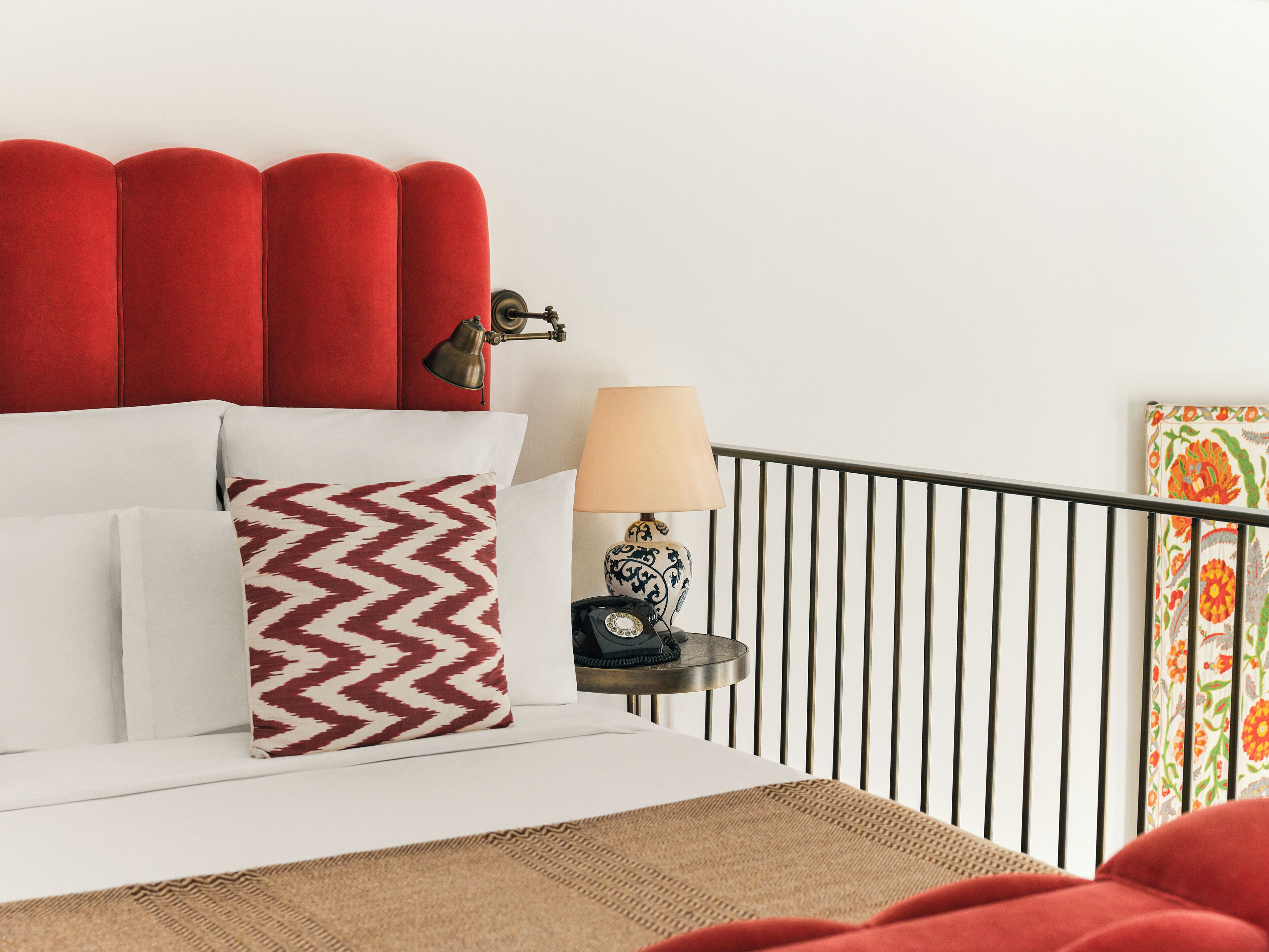 A neatly arranged hotel room with a bed, a bedside table with a lamp, and a decorative item.