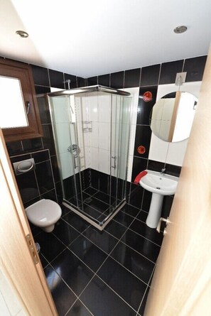A bathroom with a glass-enclosed shower, a toilet, and a sink. - Medusa Luxury Apartments (Corfu)