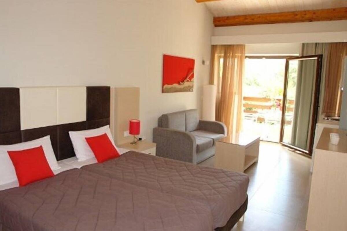 Een hotelkamer met een bed, een stoel, een bureau en een raam met gordijnen.