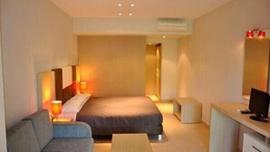 Een moderne hotelkamer met een bed, een bureau, een stoel en een kleine bank.