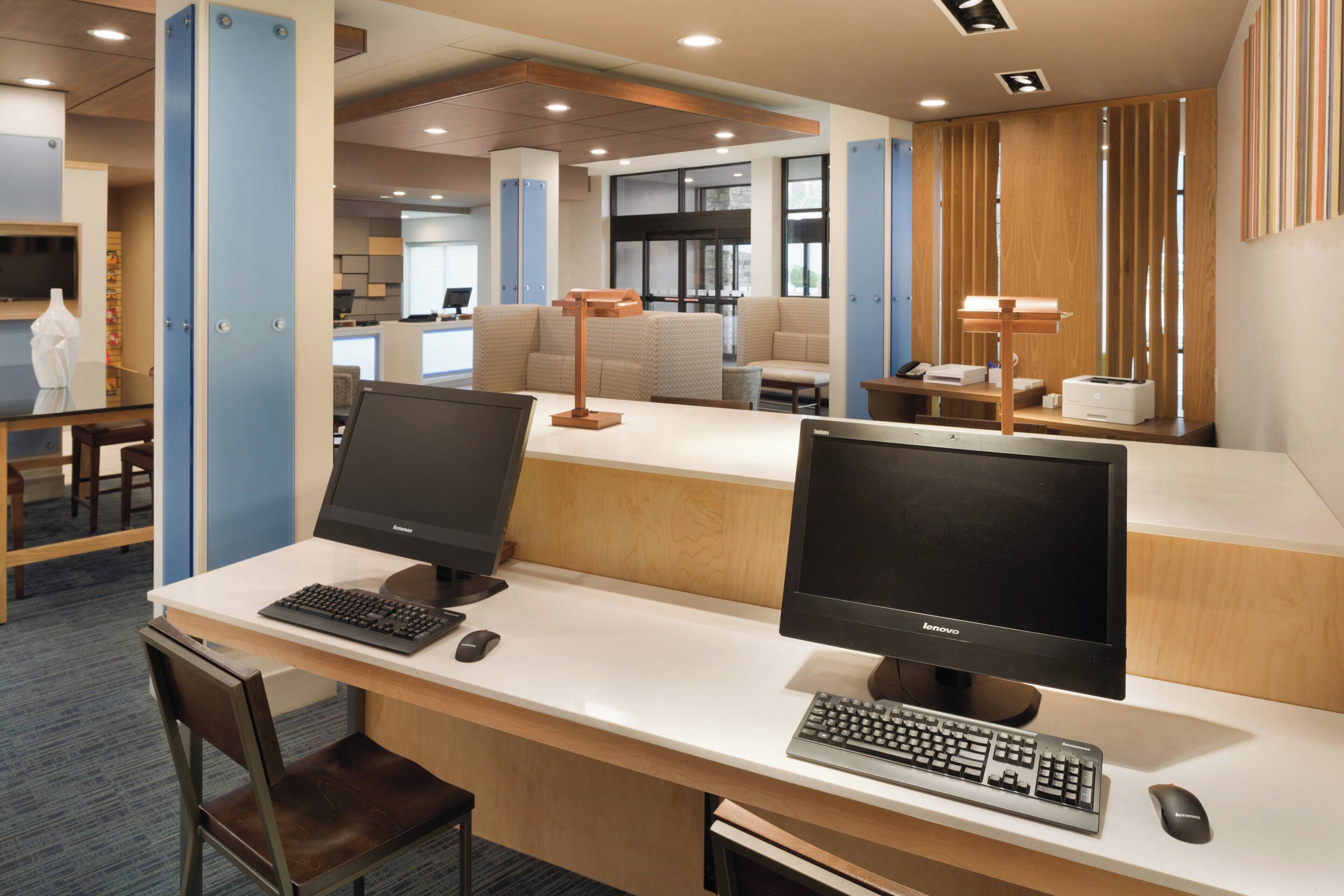 A modern office space with two desks, each equipped with a computer monitor, keyboard, and mouse.