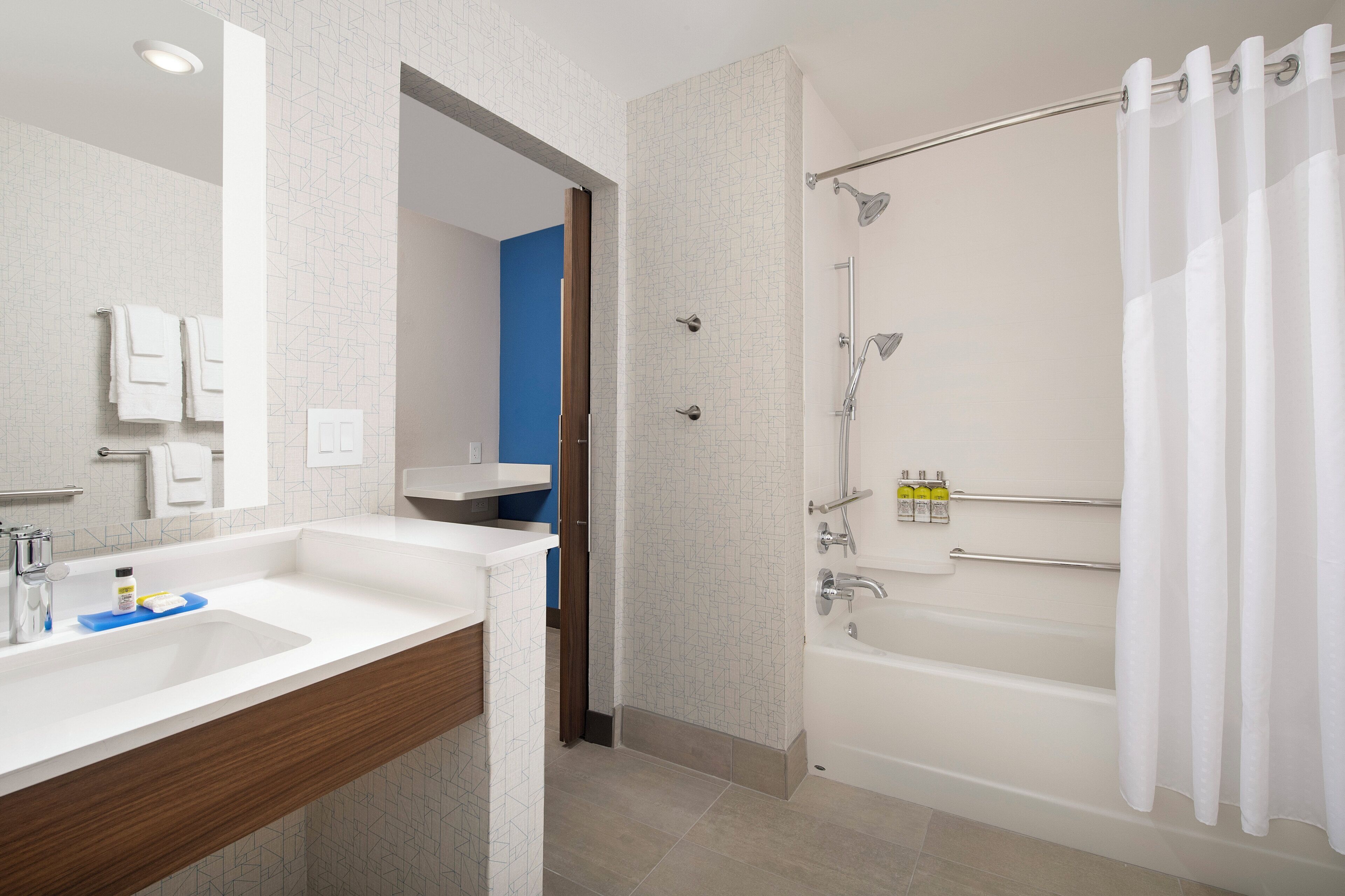 A modern bathroom with a shower, a sink, and a mirror.
