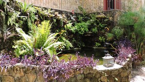 A stone building with a small pond and lush greenery. - Araújo Bazilio Pousada Tiradentes (Tiradentes)