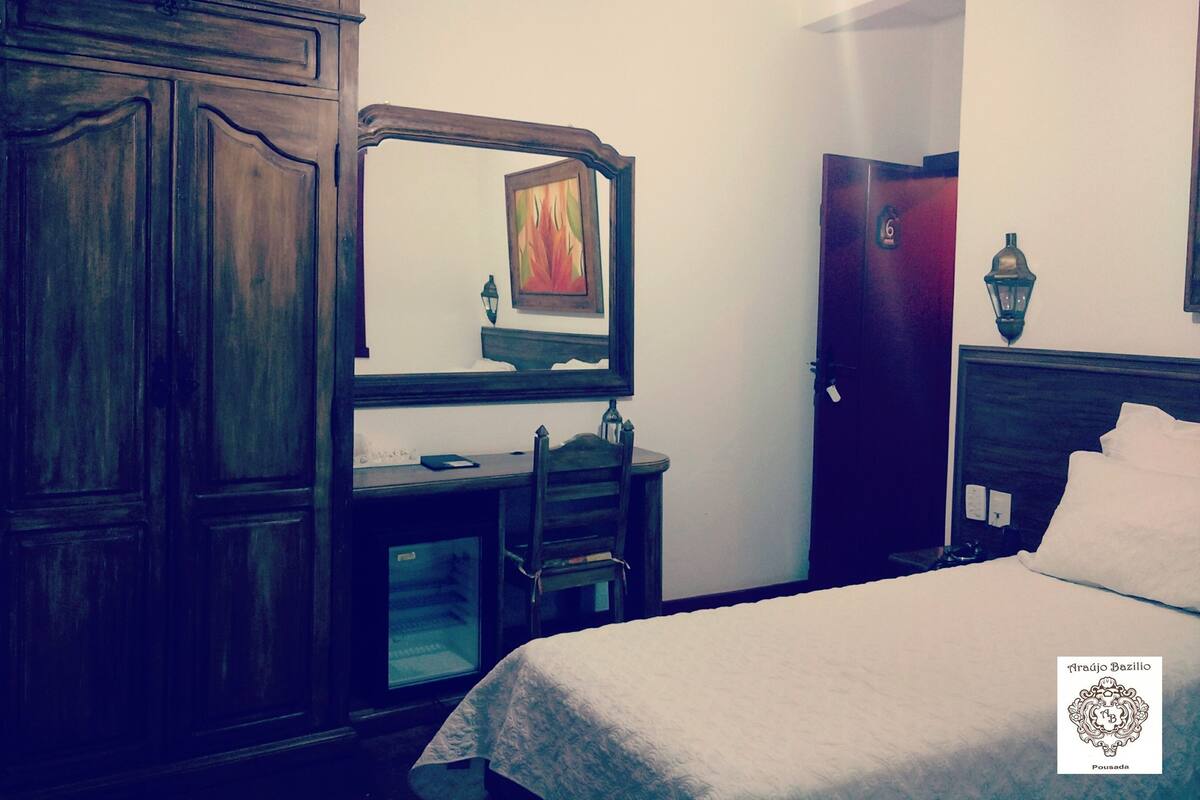 A bedroom with a bed, a dresser, a mirror, and a door.