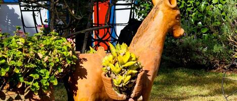 A garden with a wooden horse sculpture carrying a potted plant.
