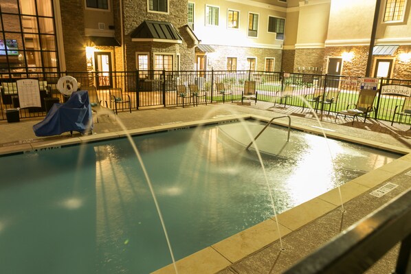An indoor swimming pool with a covered slide, surrounded by a fence and chairs, with a building in the background. - Staybridge Suites Austin North - Parmer Lane by IHG (Austin)