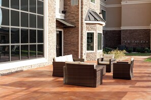 A patio with wicker furniture and a stone wall. - Staybridge Suites Austin North - Parmer Lane by IHG (Austin)