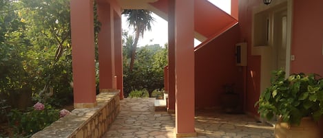 A stone-paved pathway leading to a building with pink walls and a potted plant.