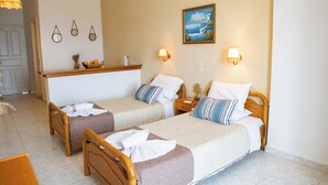 A hotel room with two single beds, a wooden headboard, a small table with a basket of fruit, and a painting on the wall. - Villa Bambas (Corfu)