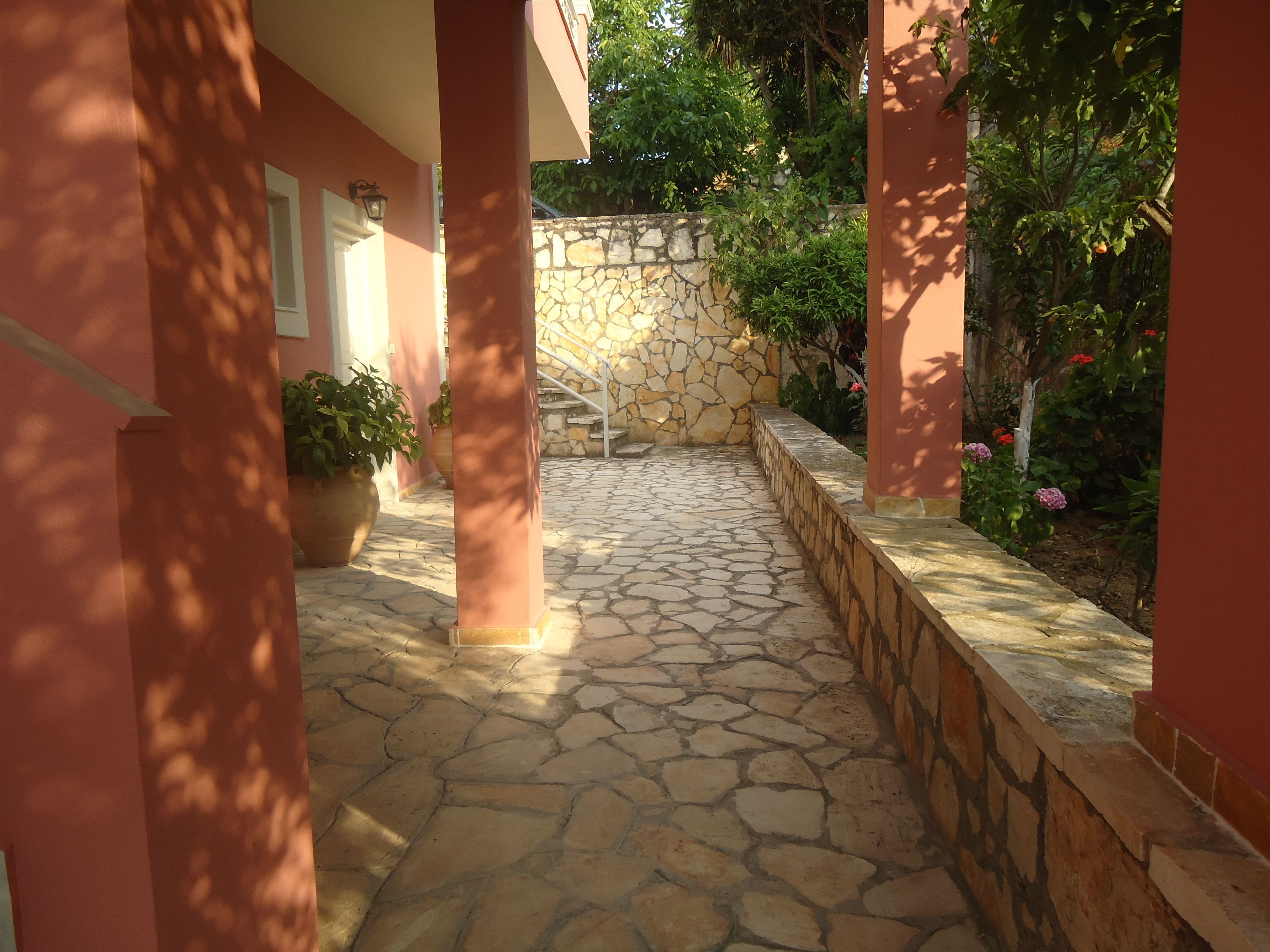 Um pátio com piso de pedra, uma parede de pedra e uma escadaria que leva a um nível superior.