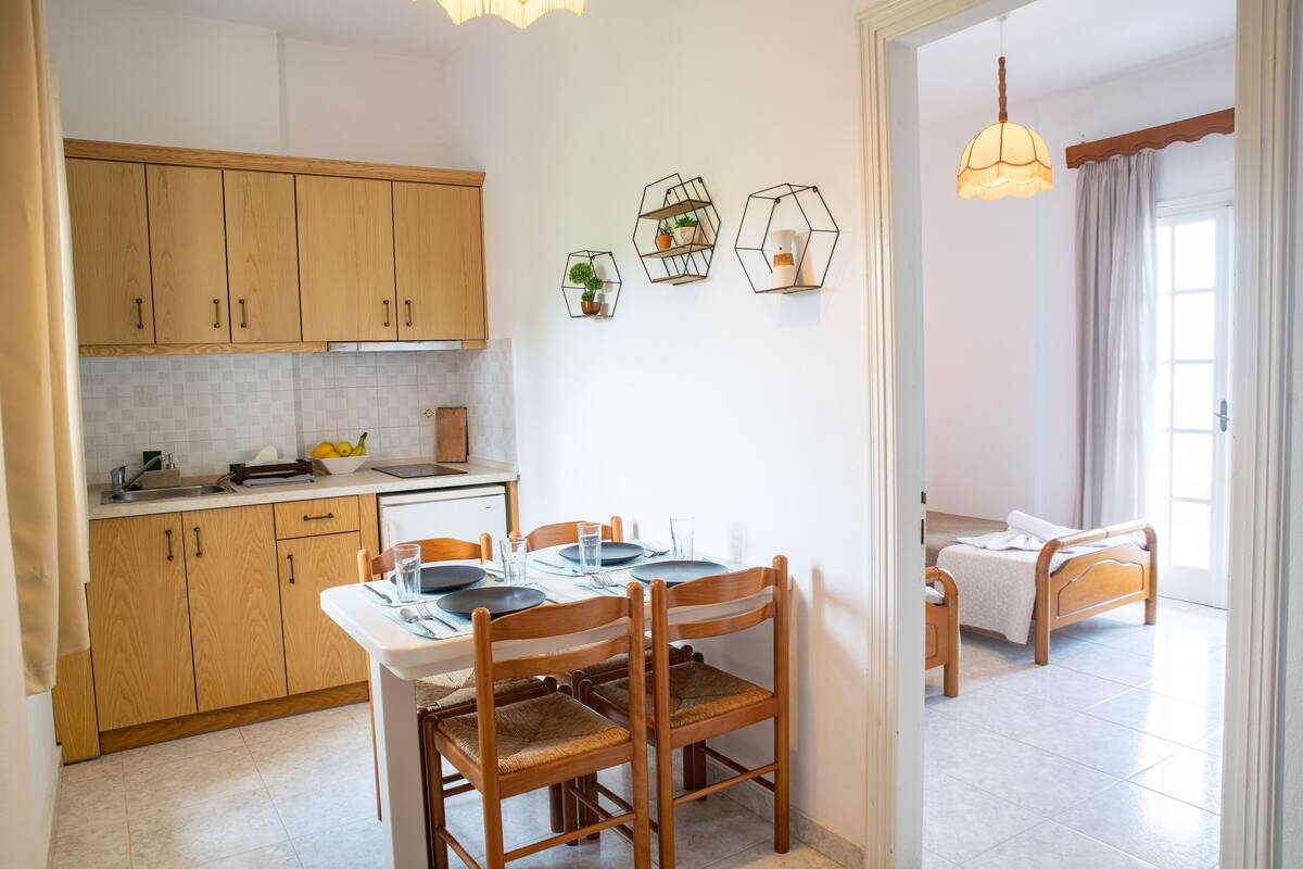 A modern kitchen with wooden cabinets, a dining table set for four, and hexagonal wall sconces.