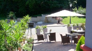 An outdoor patio with brick flooring, outdoor furniture, and potted plants. - Hotel Markgräfler Hof (Badenweiler)