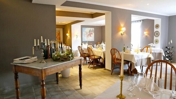 A dining area with a wooden table set for a meal, surrounded by chairs. - Hotel Markgräfler Hof (Badenweiler)