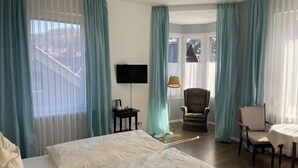 A hotel room with two beds, a TV, a chair, a table, and a lamp. - Hotel Markgräfler Hof (Badenweiler)