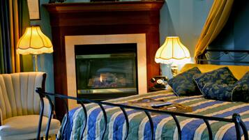 A bedroom with a bed, a chair, a fireplace, and lamps.